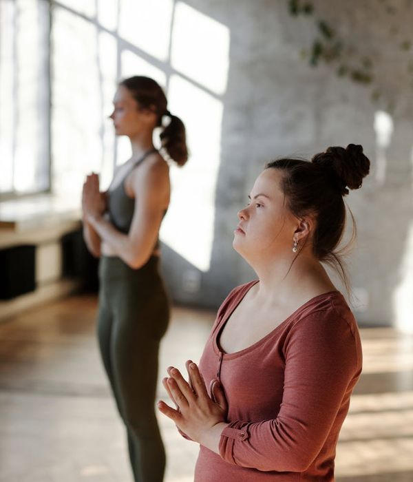 Woman in a peaceful yoga pose in a bright, sunlit room.